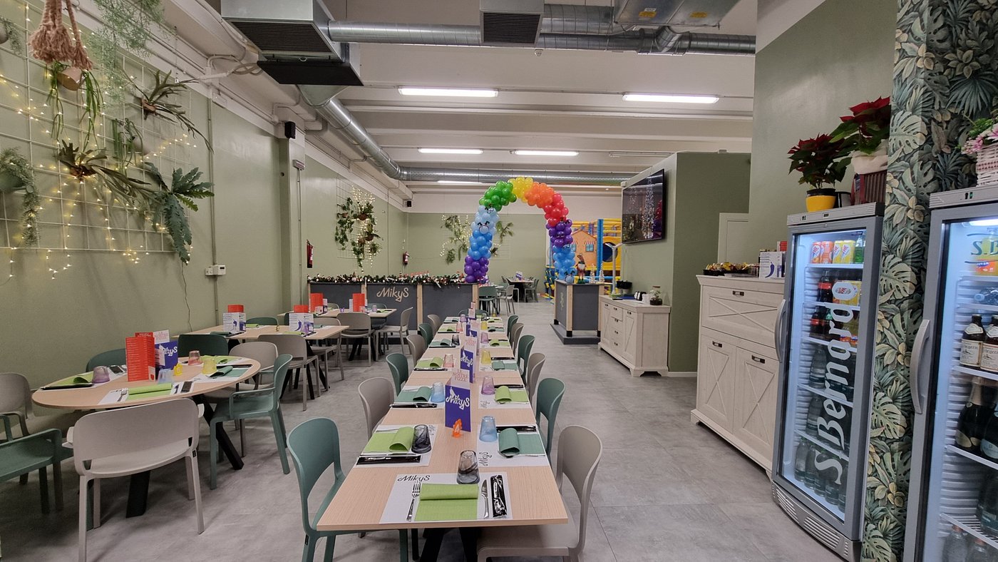 Sala principale della pizzeria MikyS a Flero con tavoli apparecchiati, pareti verdi e arco di palloncini